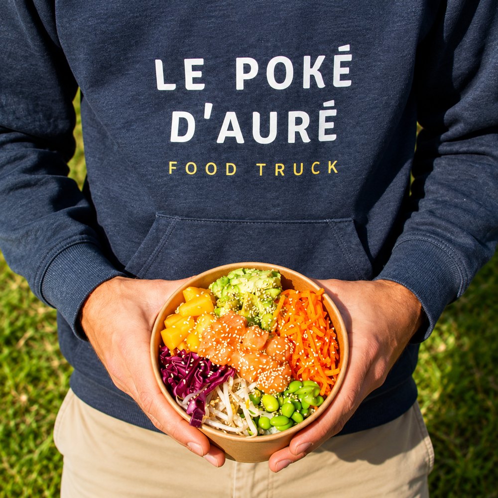 Un poké bowl tenu à deux mains devant le sweat Le Poké d'Auré Food Truck